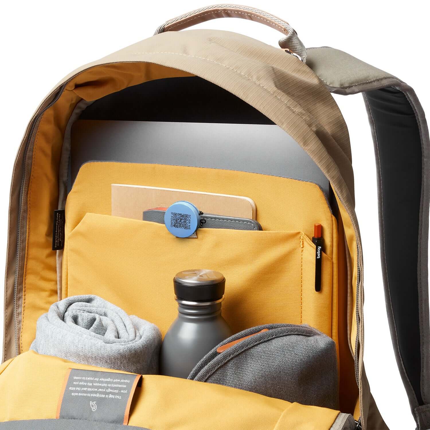 Interior of a stylish backpack featuring a laptop, notebooks, and a Roam smart finder for easy tracking.